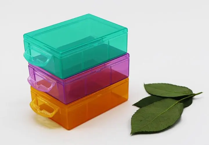 Three-layer colorful plastic storage boxes, the boxes are green, purple and orange, and there are two green leaves next to them